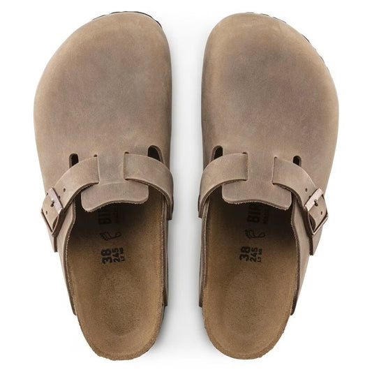 Two taupe-colored leather clogs with buckles on the side.