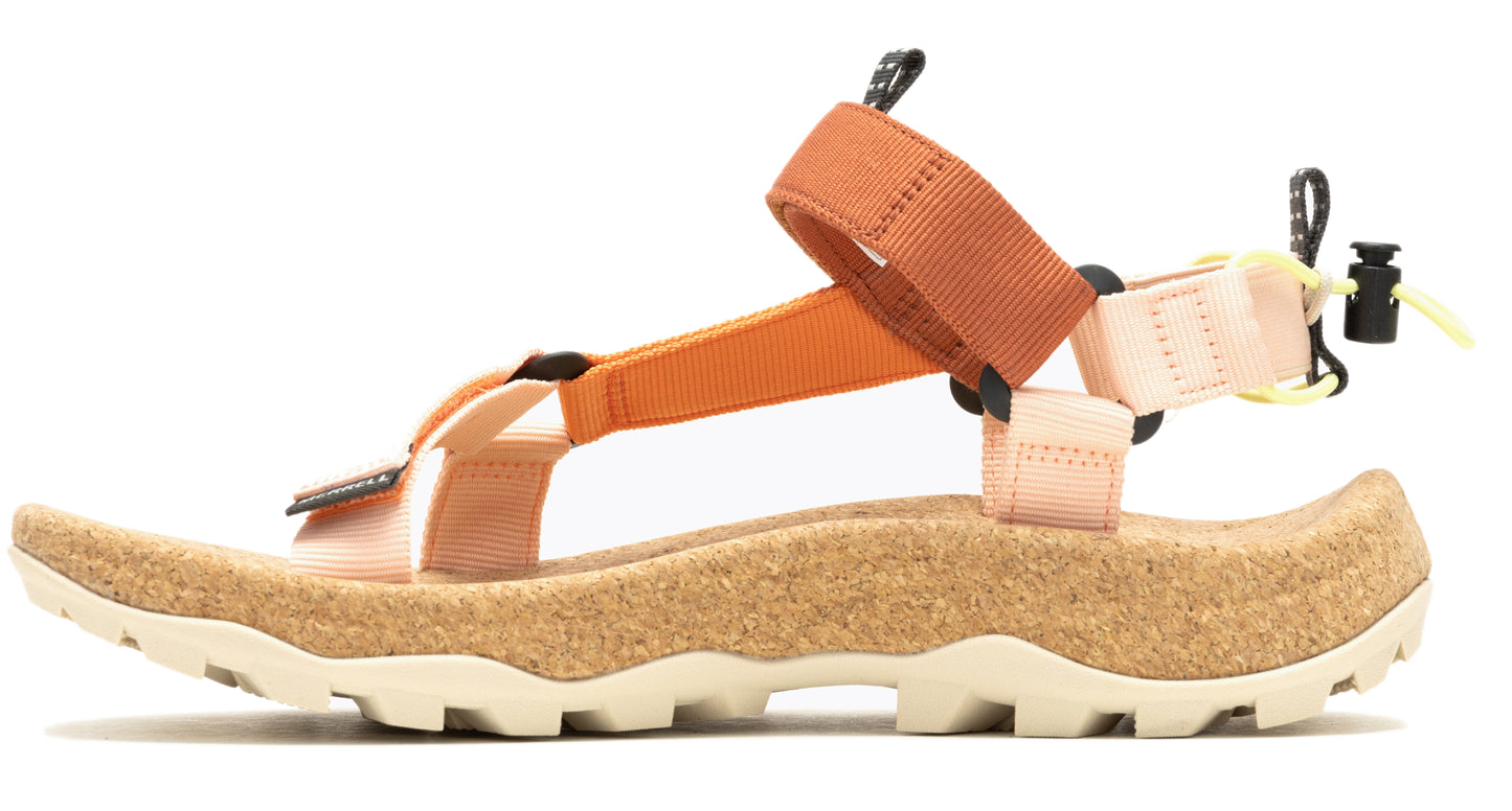 Side view of a hiking sandal with cork footbed, peach-colored and orange straps, black accents, and a white lug sole.