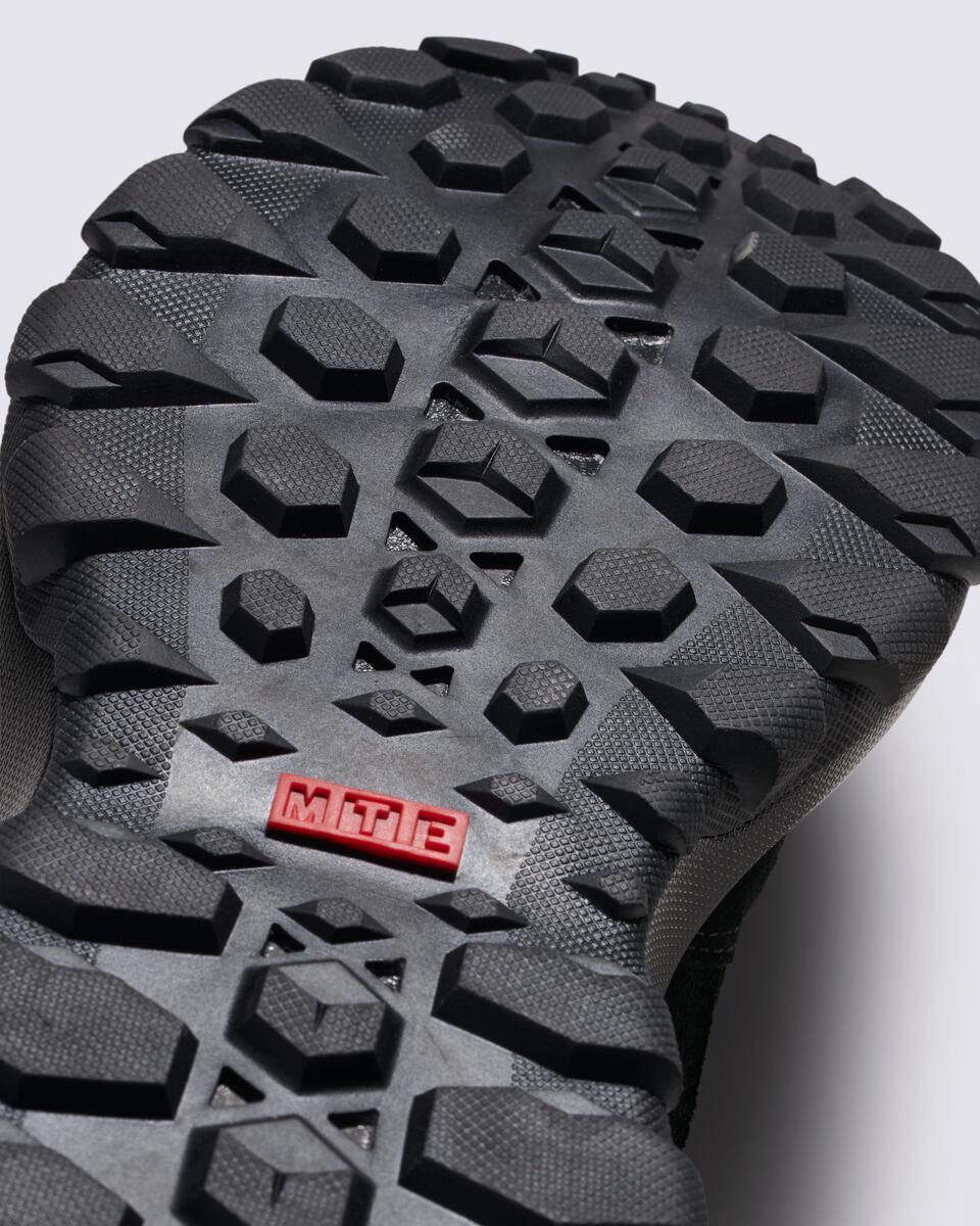 Close-up of a shoe sole showing a complex pattern of rubber treads and an inset rectangle with "MTE".