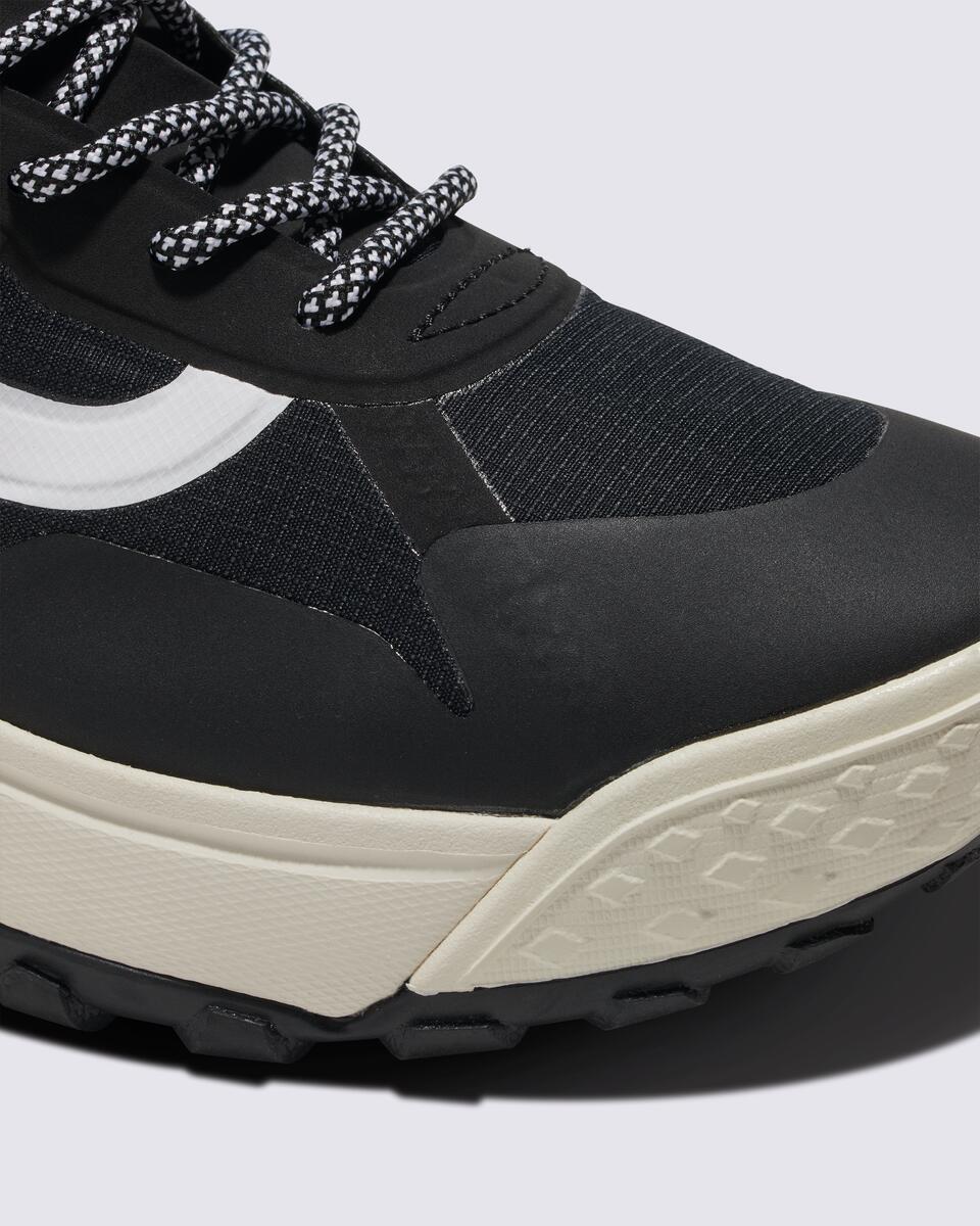 Close-up of a black sneaker featuring a white stripe and patterned laces.