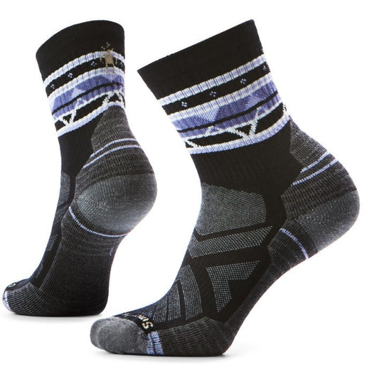 A pair of black socks with a purple and white geometric pattern near the top.