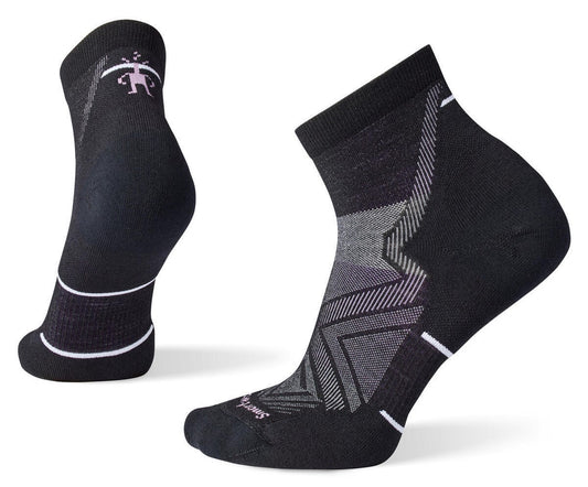 Two black socks, one ankle length with geometric pattern and Smartwool logo at the toe, one sock is standing upright showing the back with a small figure and white stripes.