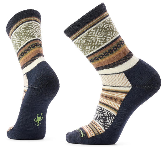 A pair of crew-length wool-blend socks featuring an intricate, multi-colored pattern with geometric bands in shades of dark blue, cream, tan, and olive green, with a small green icon on the back of the heel and the brand name on the toe.