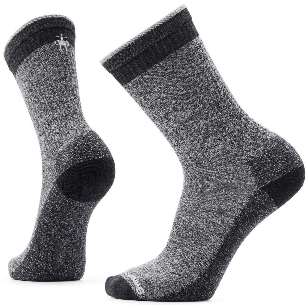 A pair of grey, charcoal, and black wool hiking socks in a mid-calf crew length with ribbed cuffs and a Smartwool logo on the top of the foot.