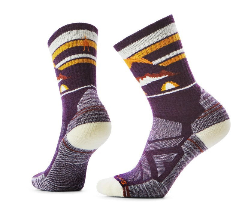Two purple socks with white heels and toes featuring orange, brown, and white stripes with a mountain and camping scene design.