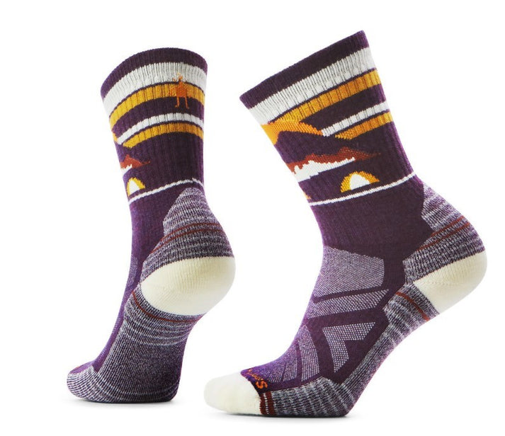 Two purple socks with white heels and toes featuring orange, brown, and white stripes with a mountain and camping scene design.