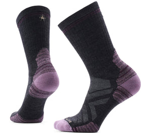 A pair of black crew-length hiking socks with purple accents on the toe, heel, and arch, featuring visible gray reinforced panels and a small logo embroidered at the top cuff.