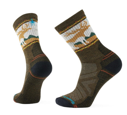 Two green socks with a white band around the top featuring a reindeer and mountain range design.