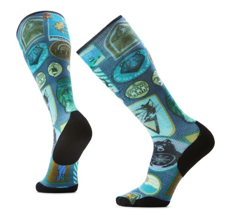 Two patterned blue socks, knee-high, with images of bears, mountains, and outdoor scenes; toe and heel are black.