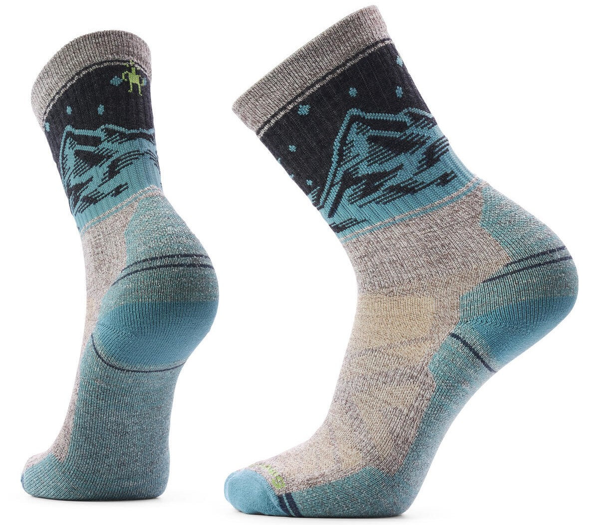 A pair of crew-length hiking socks featuring a mountain range pattern in teal and navy blue on a charcoal background, with a grey cuff and light grey foot accented by blue heel and toe reinforcement.