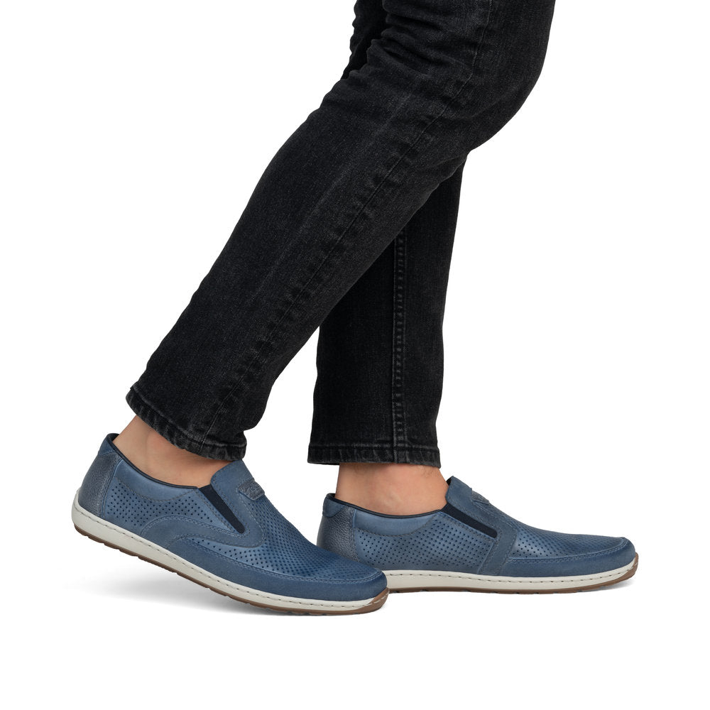 Blue leather slip-on shoes being worn with black denim jeans.