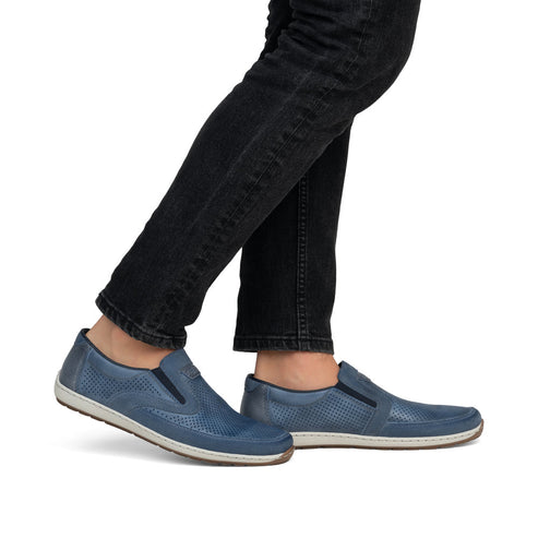 Blue leather slip-on shoes being worn with black denim jeans.