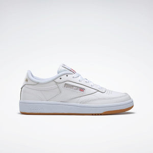 White low-top sneaker with brown rubber sole, featuring perforated toe box, side logo, and white laces.