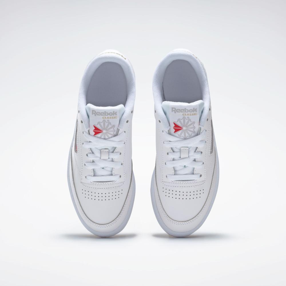 A pair of low-top white sneakers, with perforated toe, white laces, and visible 'Reebok CLASSIC' logo with a red accent.