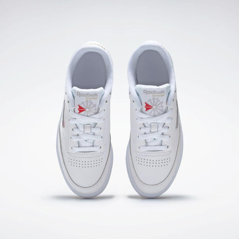 A pair of low-top white sneakers, with perforated toe, white laces, and visible 'Reebok CLASSIC' logo with a red accent.