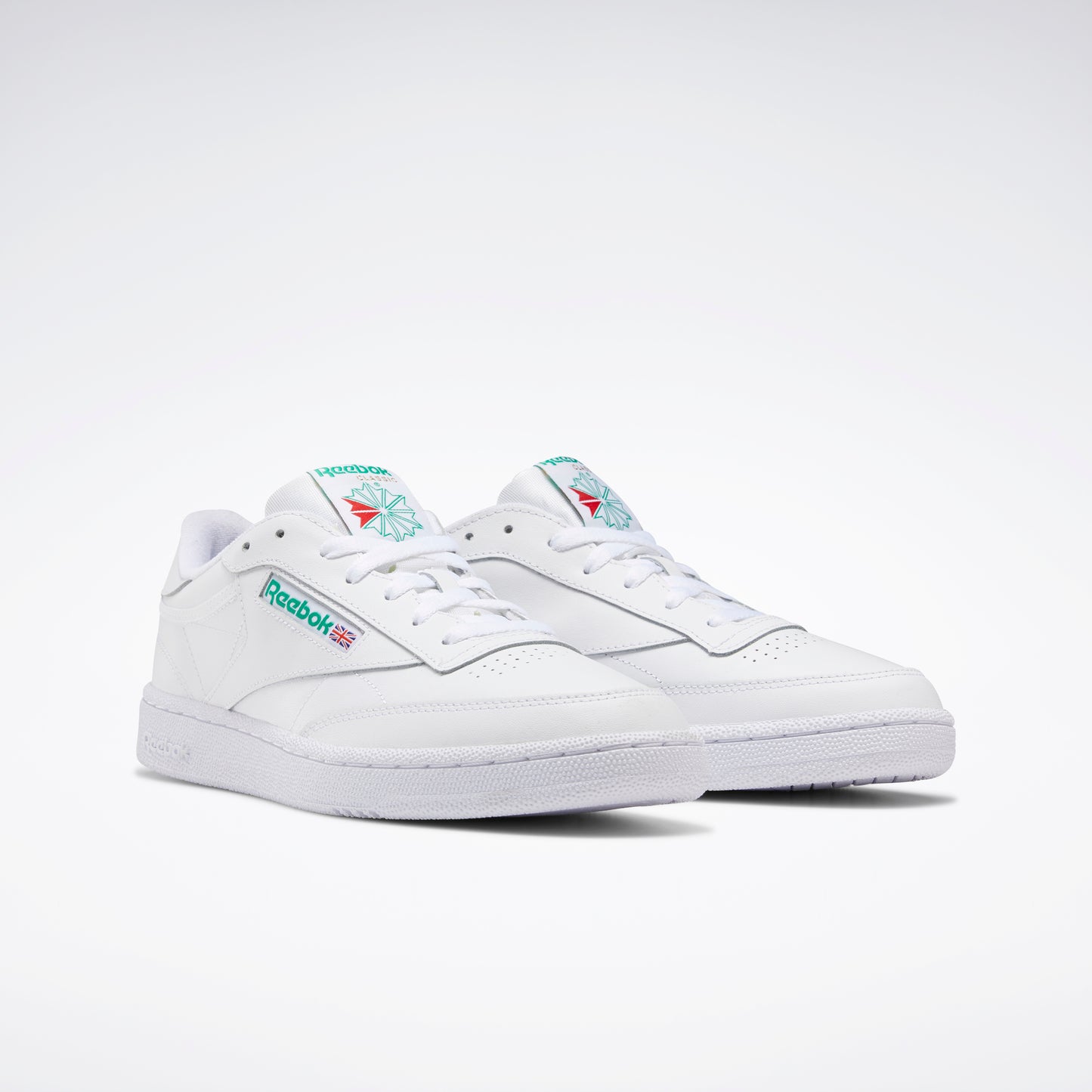 White leather sneakers with turquoise logo on tongue and side.