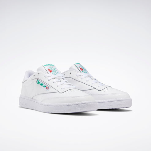 White leather sneakers with turquoise logo on tongue and side.
