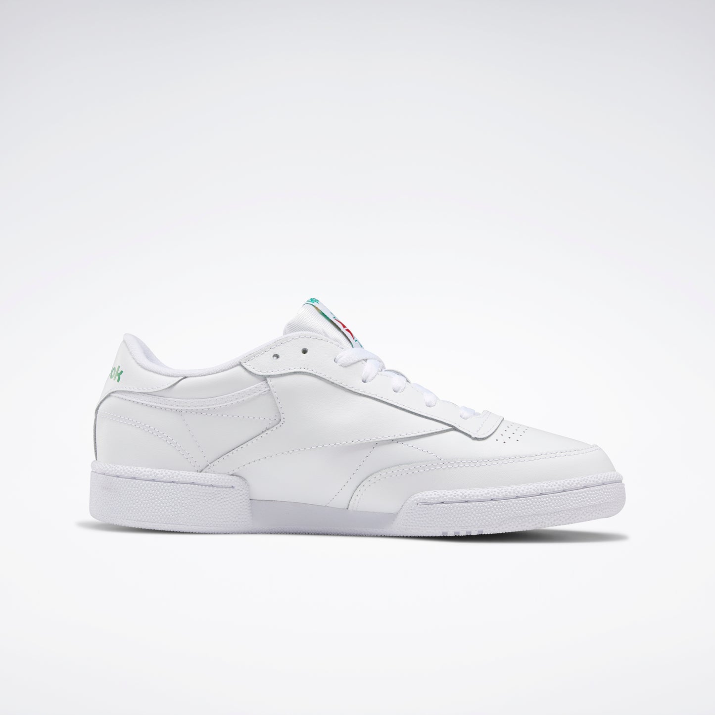 White leather tennis shoe with red and green accents on tongue and green accent on the heel.