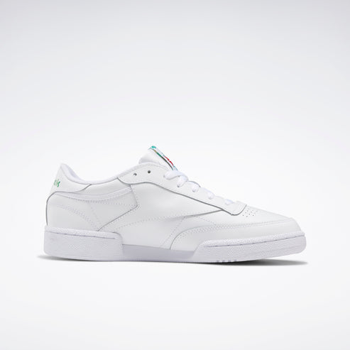 White leather tennis shoe with red and green accents on tongue and green accent on the heel.
