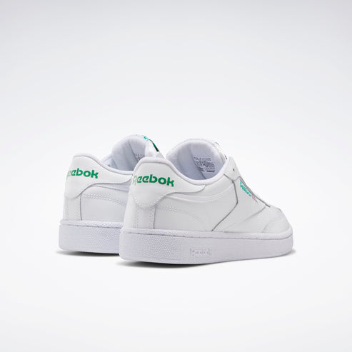 Two white shoes with green branding. The back of both shoes are shown.