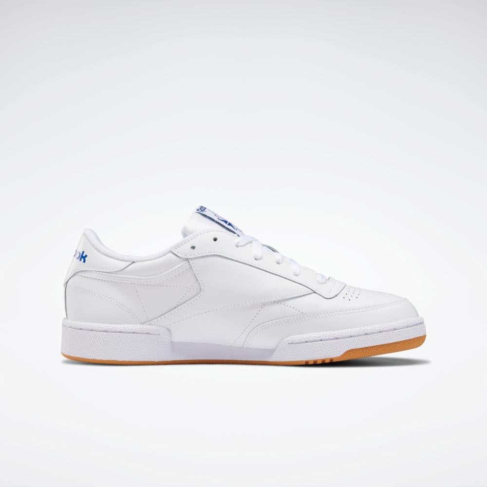White low-top sneaker with brown sole and blue logos on the heel and tongue.