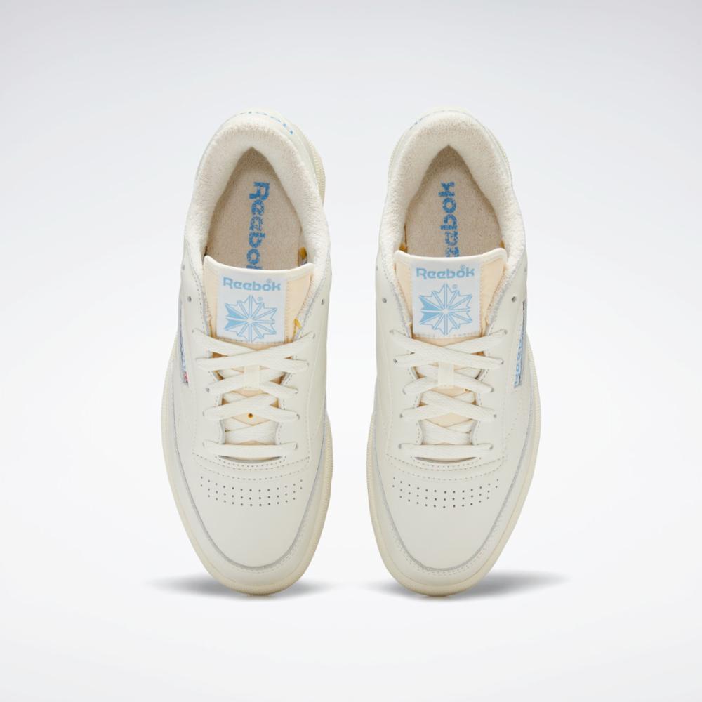 Front view of two ivory sneakers with light blue logos on the tongue and inner lining.