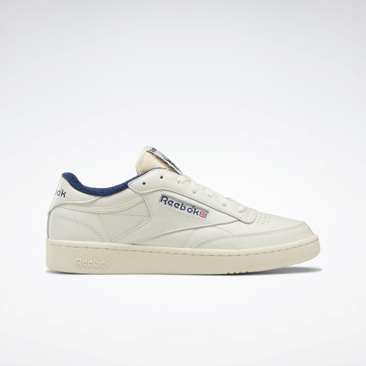 Off-white leather tennis shoe with navy blue lining and "Reebok" logo on side.