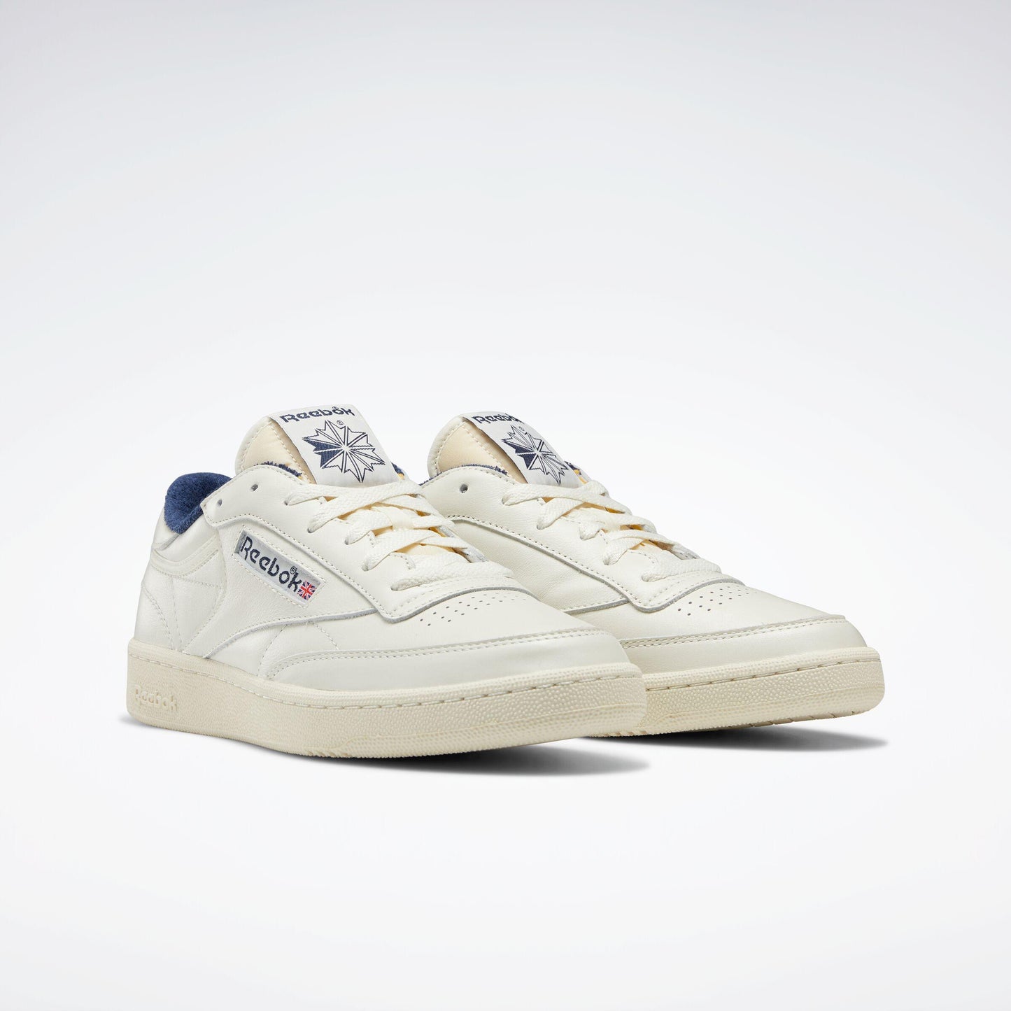 Cream-colored low top sneakers with gold laces and blue accents.
