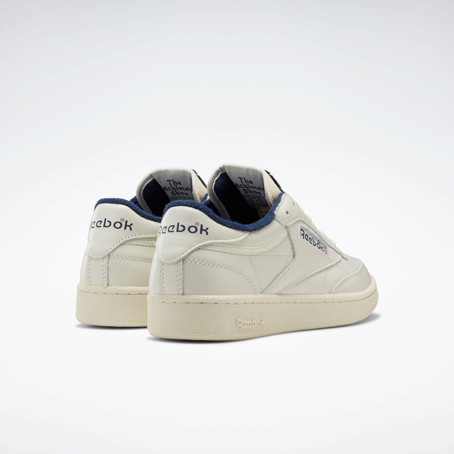 Off-white low-top sneakers with "Reebok" logo on the heel and side.