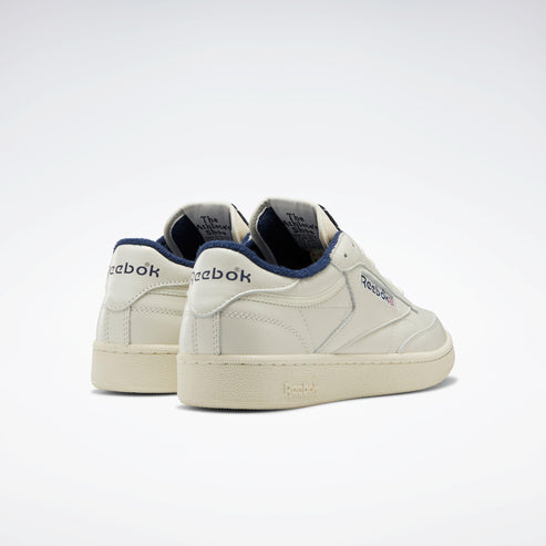 Off-white low-top sneakers with "Reebok" logo on the heel and side.