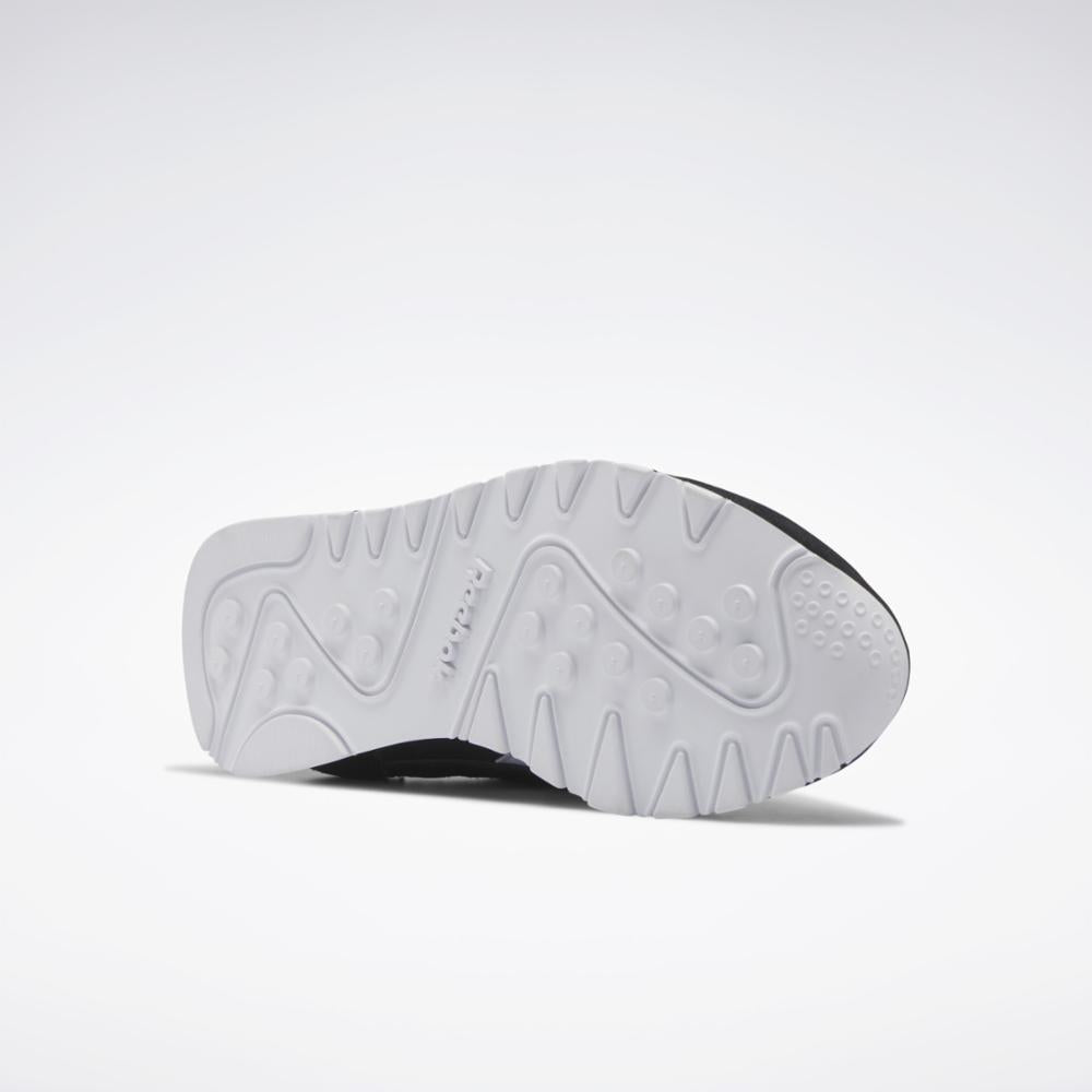 The sole of a shoe with a white textured surface and a black trim.
