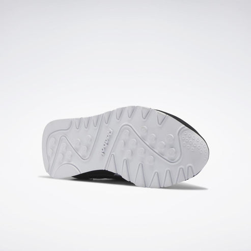 The sole of a shoe with a white textured surface and a black trim.