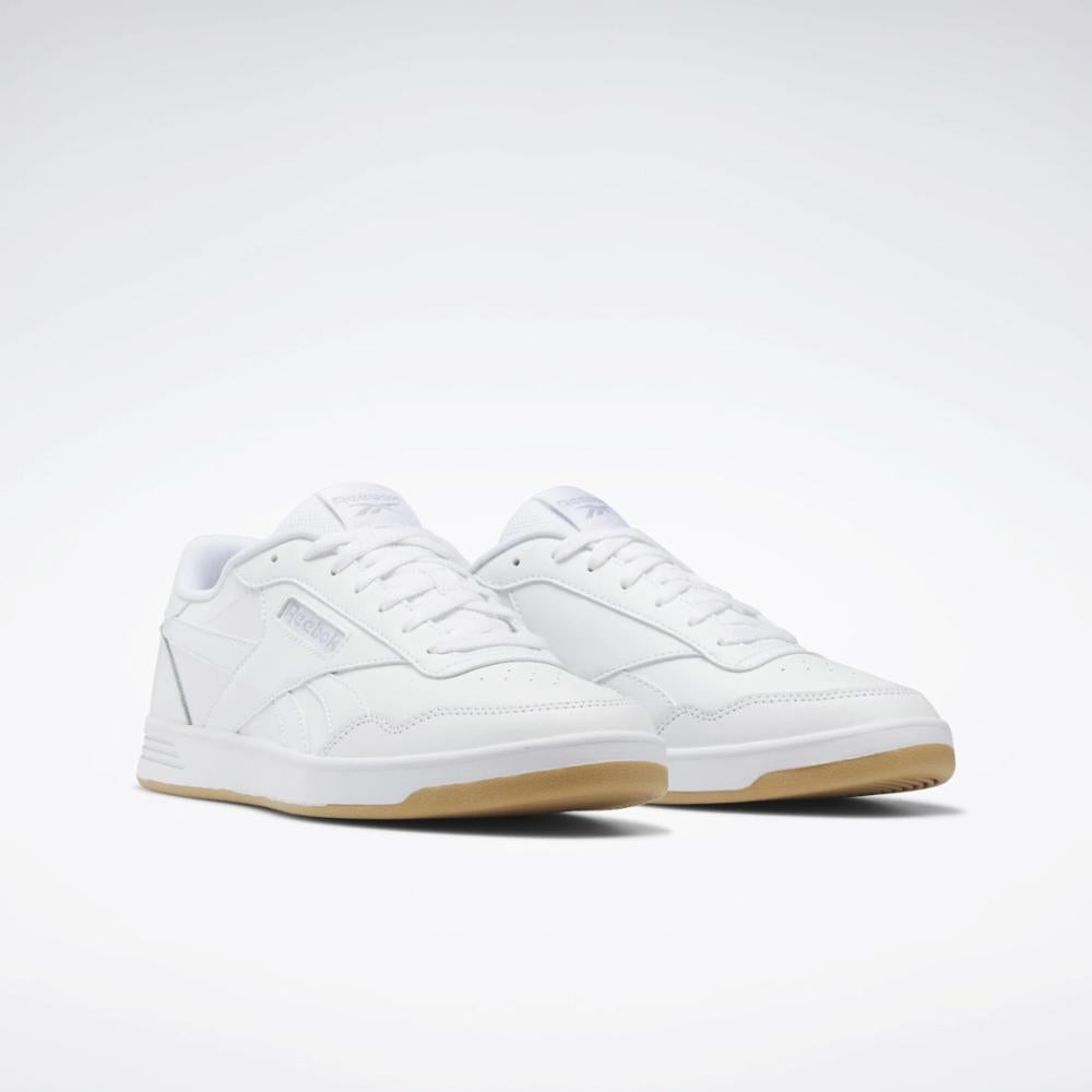 A pair of white court sneakers with gum soles.