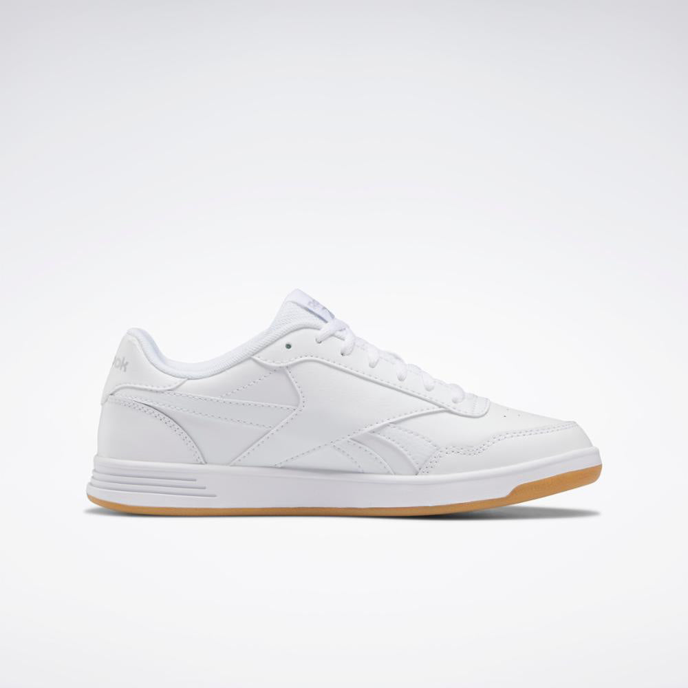 A low-top, all-white sneaker with white laces and a gum sole.
