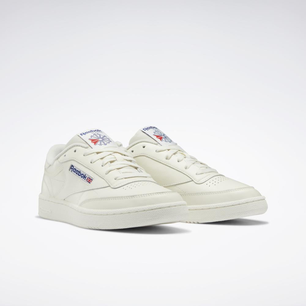 Off-white sneakers with white laces, rubber sole, and small logo detail near the heel.