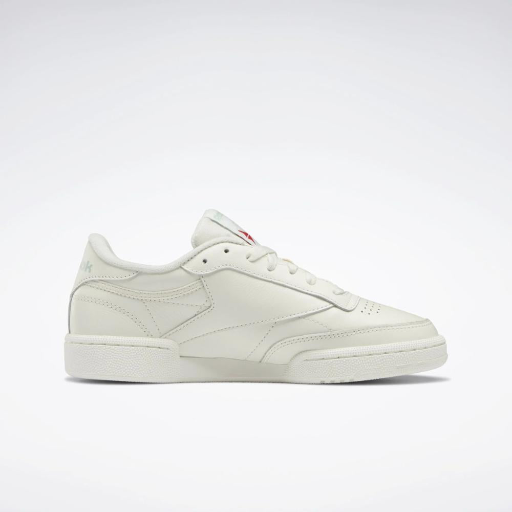 Off-white leather tennis shoe with red logo.