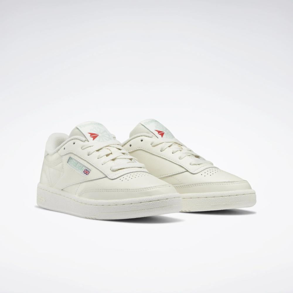 Pair of off-white leather sneakers with red logo on tongue and blue logo on side.