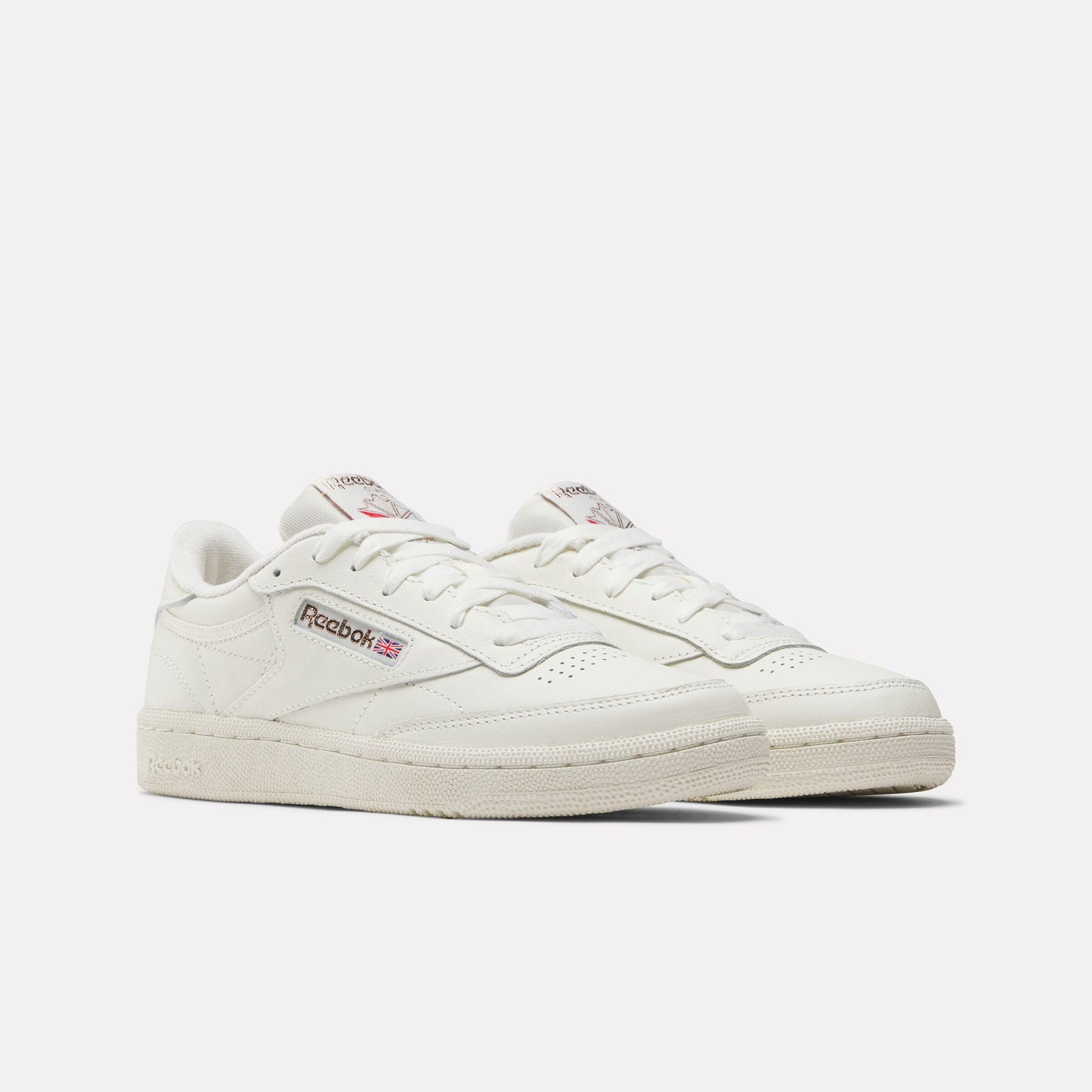 Off-white leather low-top sneakers with perforated toe box, and logo detail.