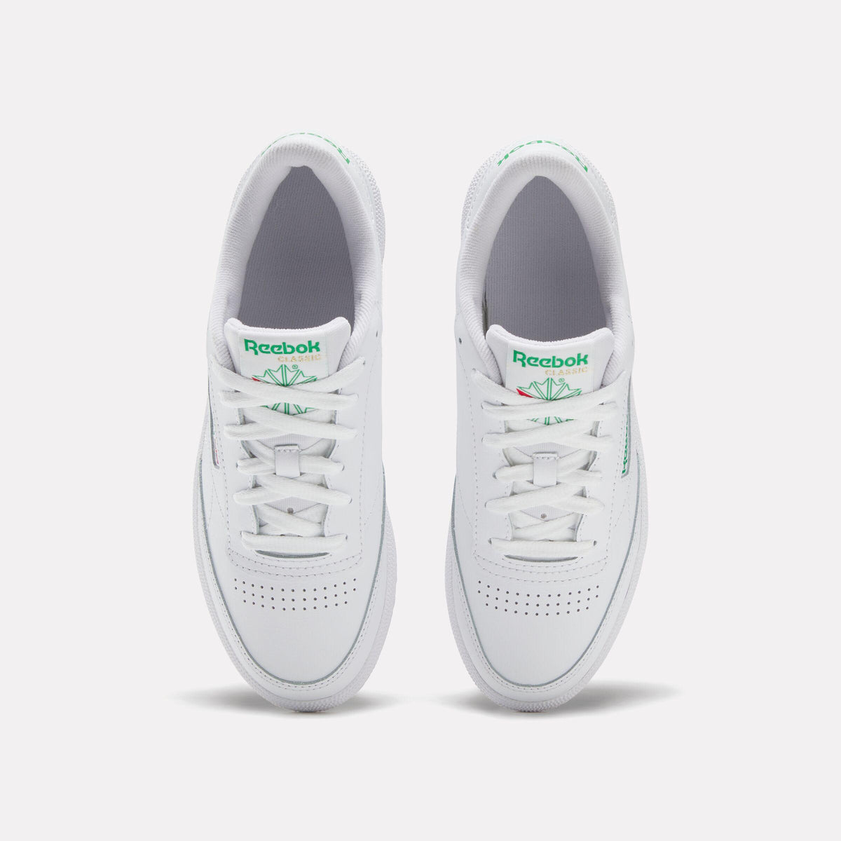 White sneakers, top view, green logo, white laces.