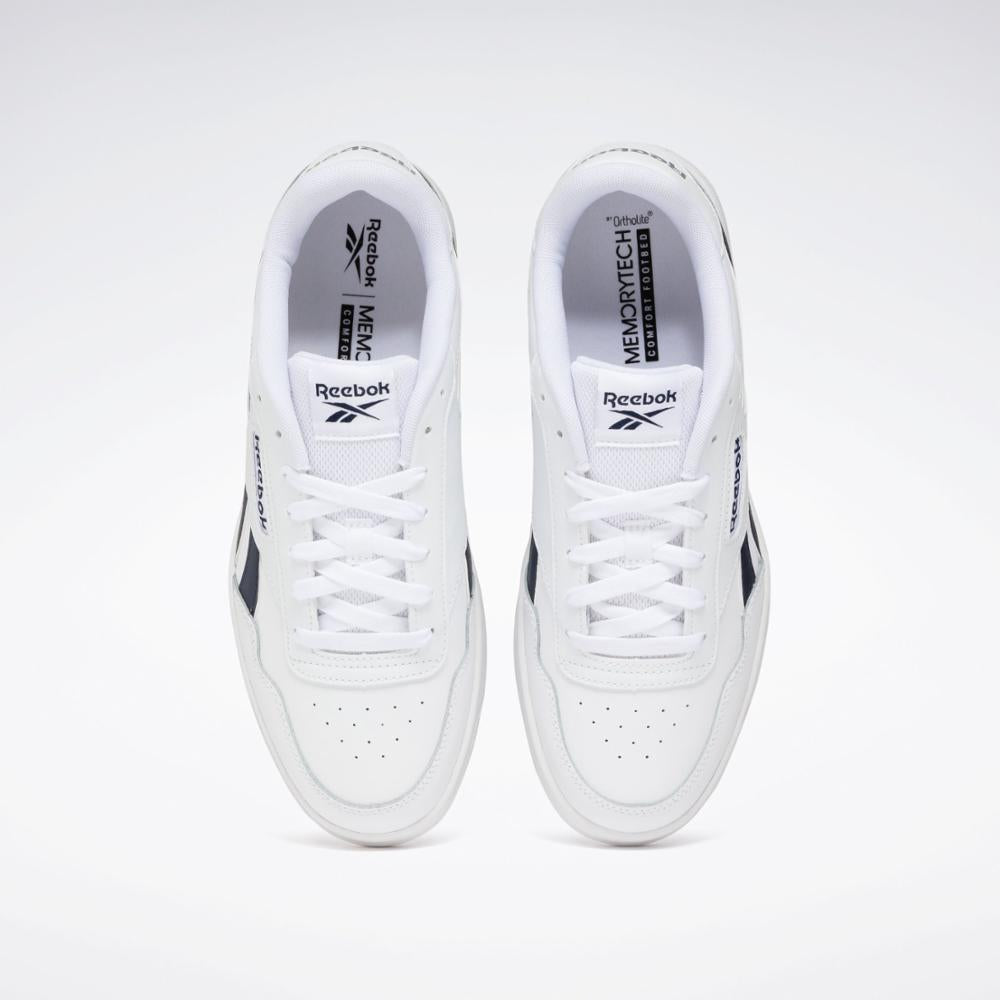 Top-down view of white athletic shoes with a perforated toe box and white laces. Black logo on the side and insole visible.