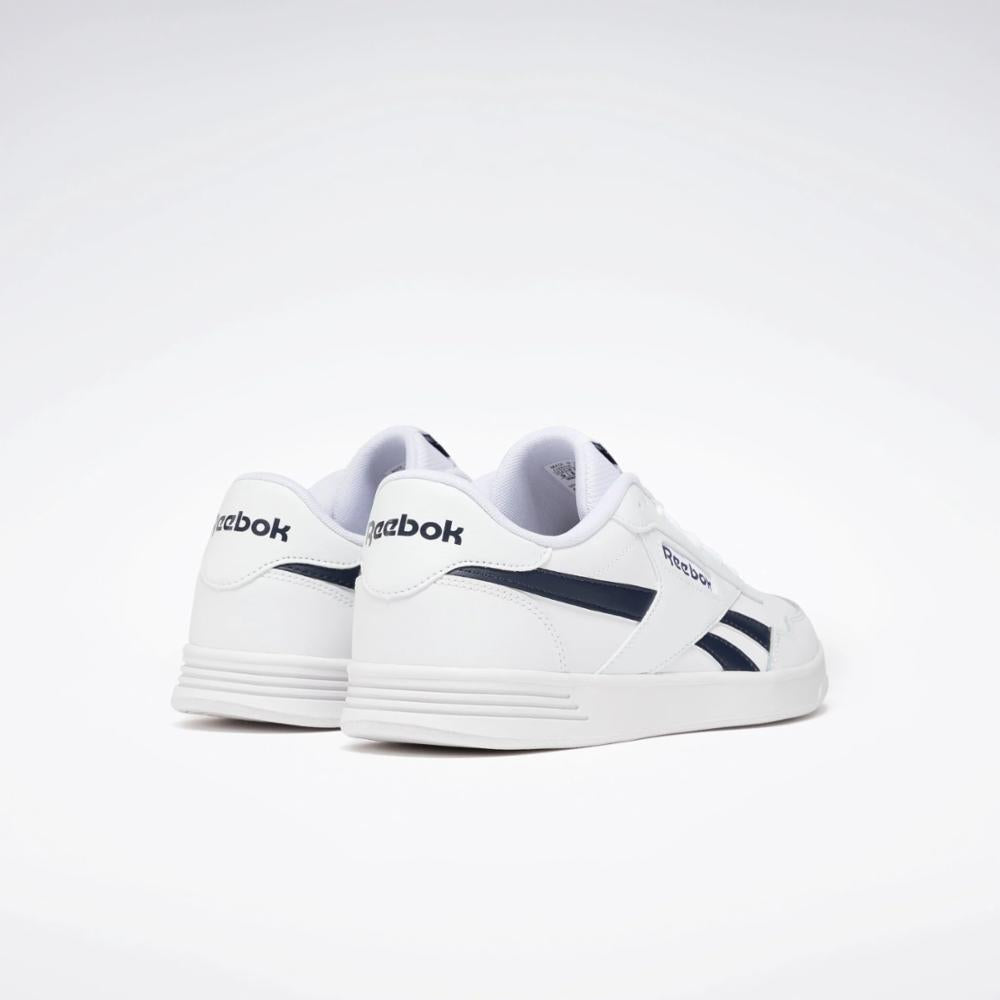 White sneakers with navy accents, featuring the word "Reebok" on the heel.