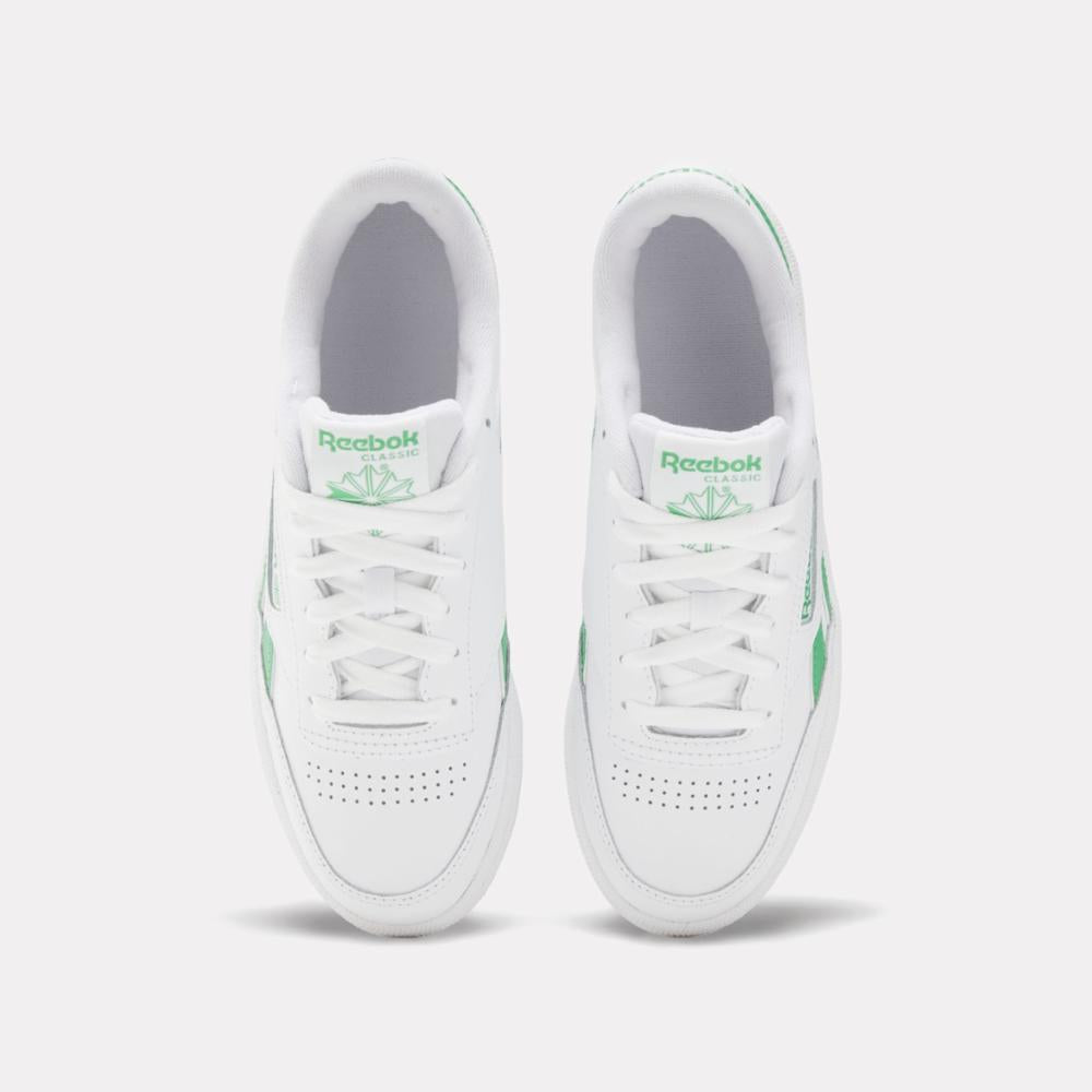 Two white sneakers with green accents and white laces.