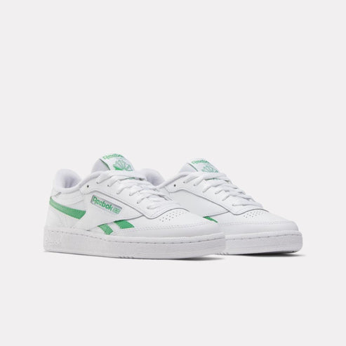 Low-top white sneakers with green accents, rubber soles and white laces.