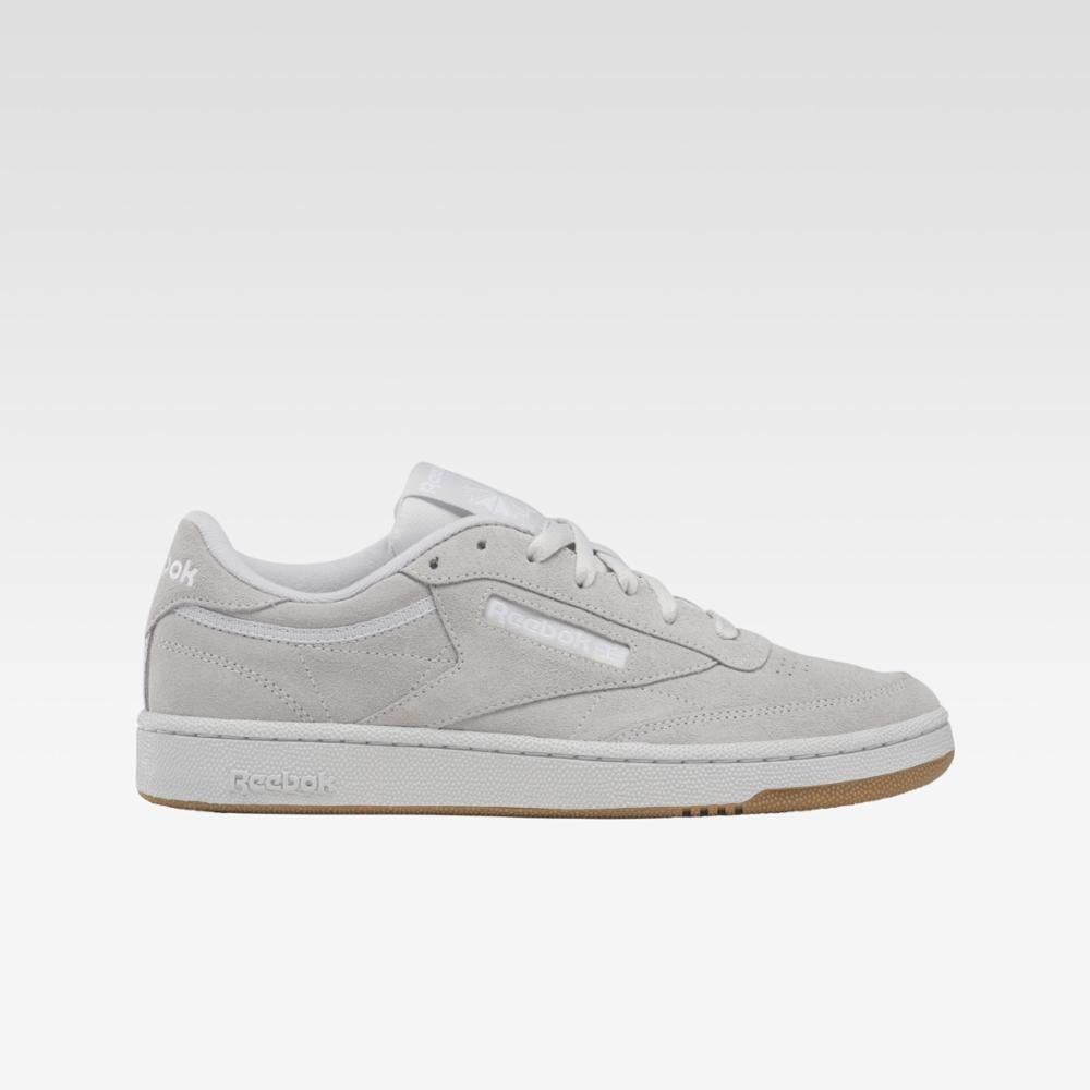 Side view of a light gray low-top sneaker with white laces and a brown sole.