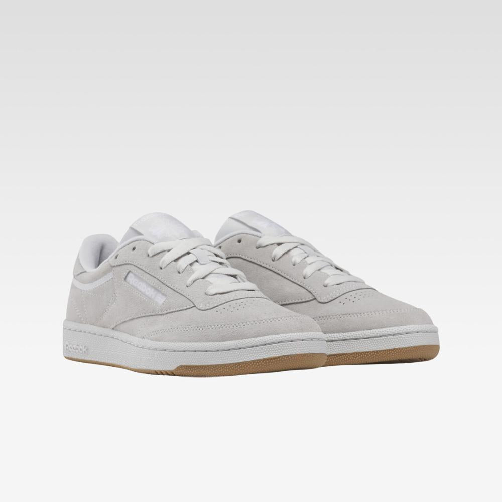 Low-profile sneakers in light gray with white laces and a tan sole.