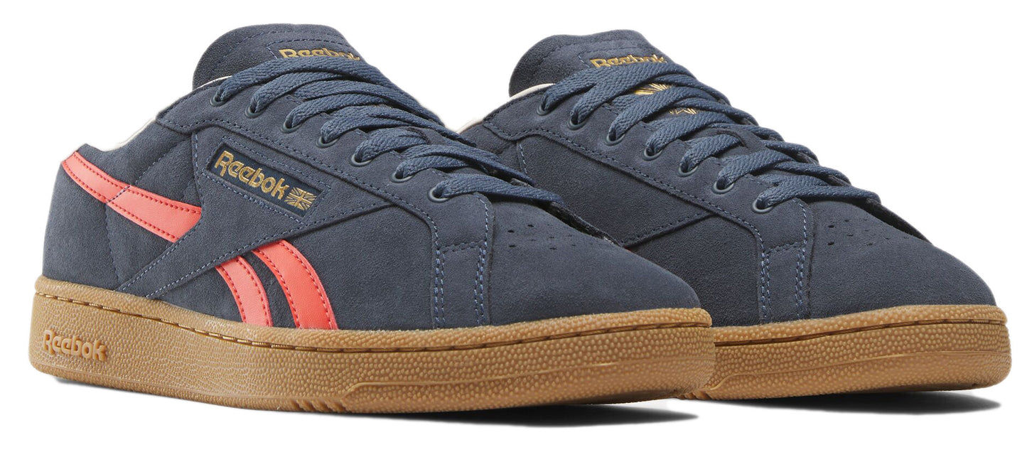 A pair of low-top blue leather sneakers with coral stripes and gum soles.