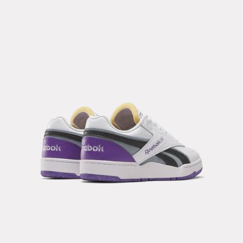 Rear view of white sneakers with purple accents, yellow interior, and the text "Reebok" in small font.