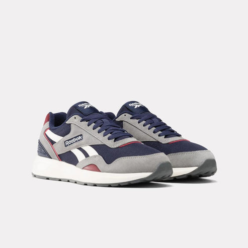 Pair of sneakers with gray, navy, red and white accents; white soles; navy laces; text "Reebok" on side.
