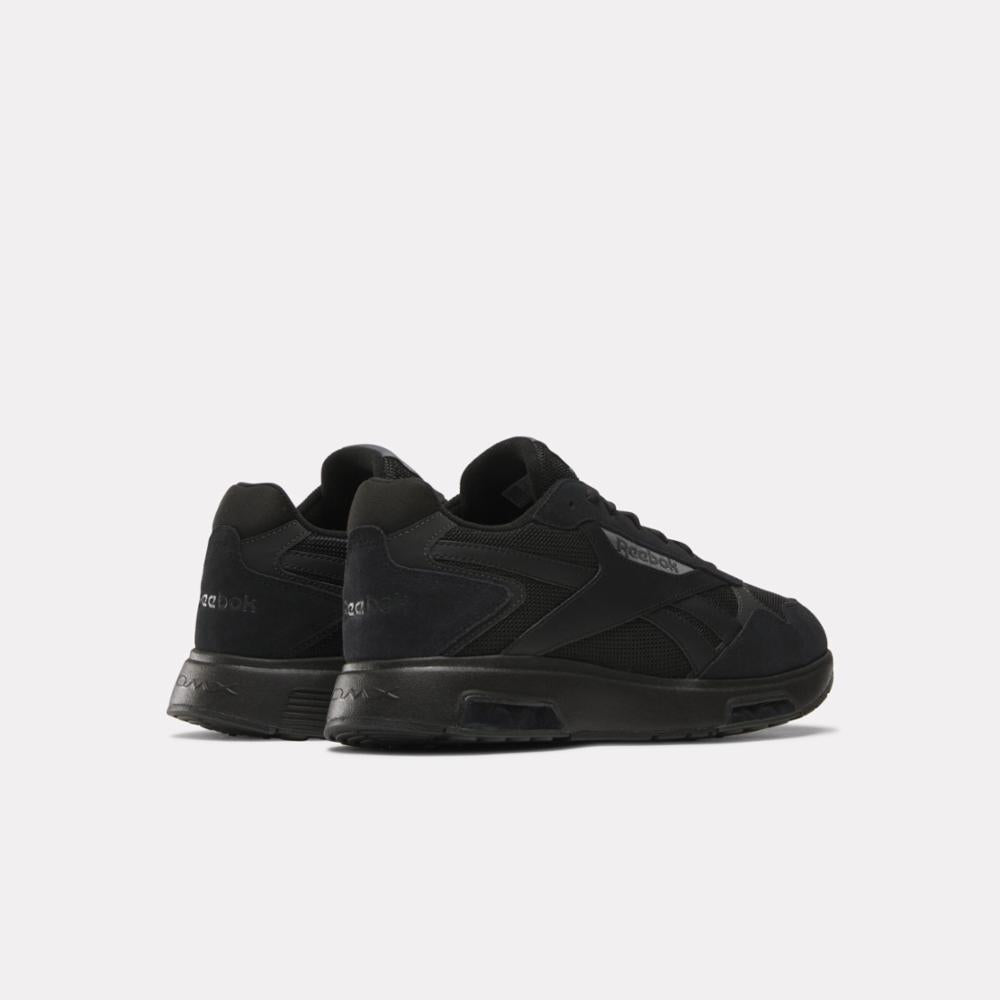 A pair of low top black shoes with flat sole and Reebok logo on side.