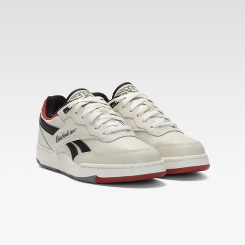 Low top sneakers with white laces, black stripes, red and black accents, and the word "Reebok".